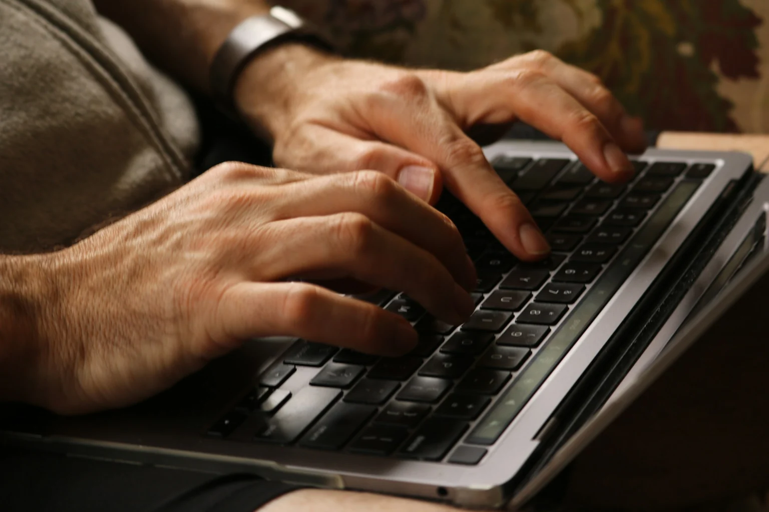 Detalhe das mãos de uma pessoa digitando no teclado de um notebook.